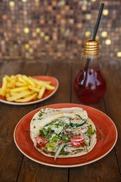 Doner z kurczaka z sałatą, ogórkiem, pomidorem i ziołami w chlebie pita