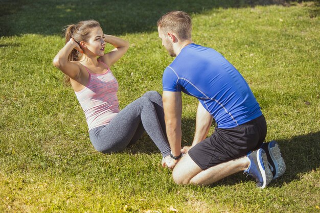 Dopasuj fitness kobieta i mężczyzna robi ćwiczenia rozciągające na świeżym powietrzu w parku