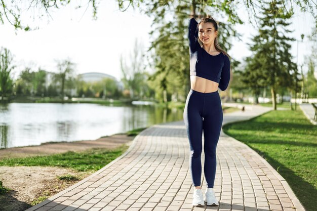 Dopasuj młoda dziewczyna w ciemnoniebieskim stroju sportowym, ćwicząc w parku