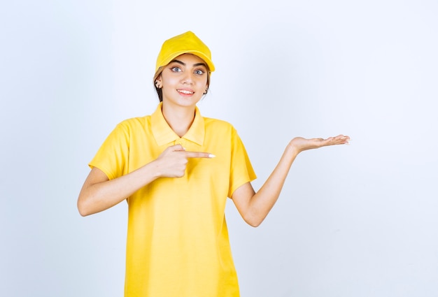 Doręczeniowa kobieta w żółtym mundurze stoi i pokazuje otwartą dłoń.