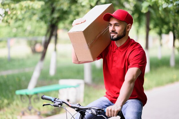 Doręczeniowego mężczyzna przewożenia pudełko na rowerze