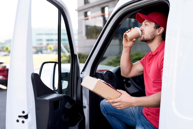 Doręczeniowy mężczyzna pije kawę w samochodzie