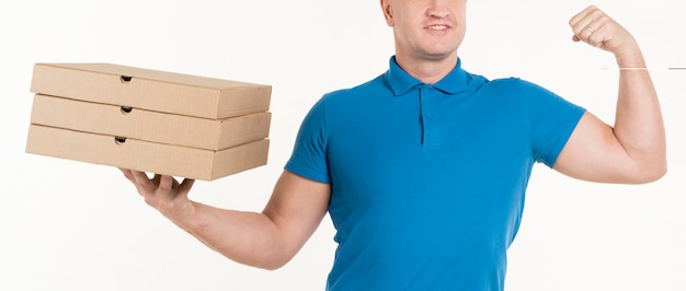Bezpłatne zdjęcie doręczeniowy mężczyzna trzyma pizz pudełka i pokazuje bicep