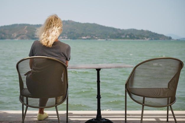 Dorosła kobieta siedząca samotnie na krześle nad morzem z poczuciem samotności obok pustego krzesła idea utraty i zdrowia psychicznego selektywne skupienie