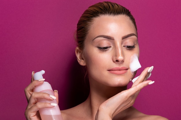 Bezpłatne zdjęcie dorosła kobieta stosuje moisturizer na jej twarzy