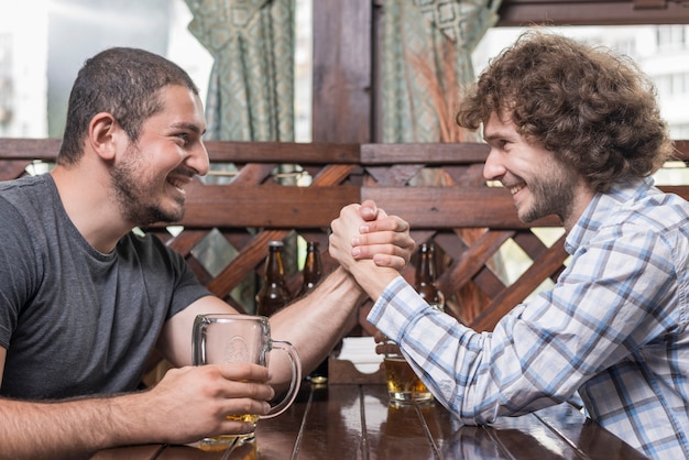 Bezpłatne zdjęcie dorosłych mężczyzn siłowanie się na rękę w pubie