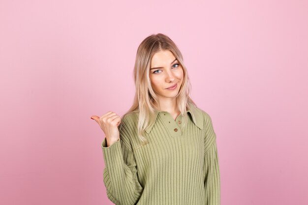 Dość europejska kobieta w swobodnym swetrze na różowej ścianie