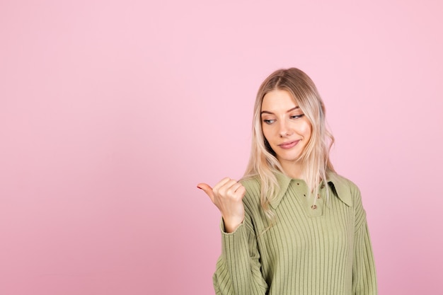 Dość europejska kobieta w swobodnym swetrze na różowej ścianie