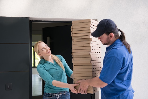 Dostawca pizzy dający pudełka po pizzy uśmiechniętej młodej kobiecie
