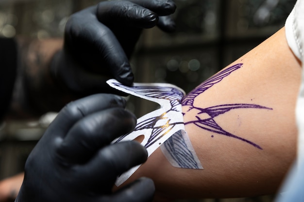 Bezpłatne zdjęcie doświadczony artysta tatuażu pracujący nad tatuażem klienta