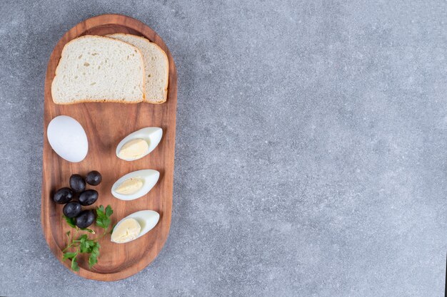 Drewniana deska do krojenia z gotowanym jajkiem i kromkami chleba
