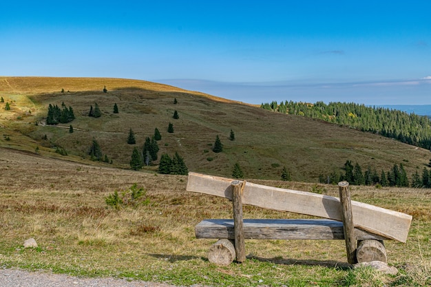 Drewniana ławka na wzgórzu, idealna do trekkingu i wędrówek pod czystym, błękitnym niebem