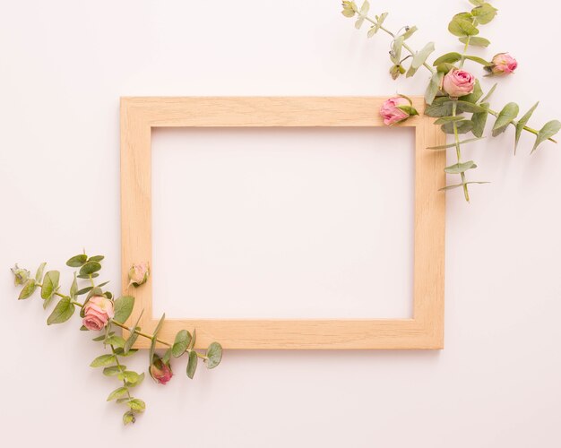 Drewniana ramka na zdjęcia ozdobiona różowymi różami i eukaliptusem