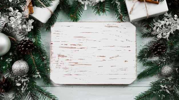 Drewniana tablica między gałęziami Bożego Narodzenia