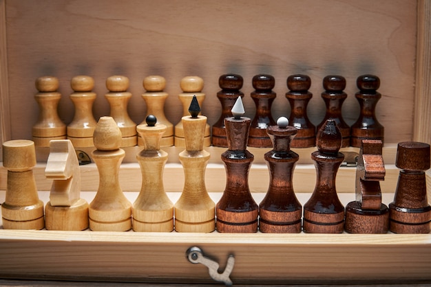 Drewniane figury szachowe w pudełku szachowym, główne figury na pierwszym planie, pionki w tle, koncepcja, strategia, planowanie i podejmowanie decyzji