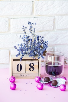 Drewniany kalendarz i filiżanka kawy ze słodyczami na stole. obchody międzynarodowego dnia kobiet 8 marca