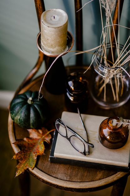 Bezpłatne zdjęcie drewniany stół ozdobiony motywem jesiennym z aromatyczną świecą, szklankami, suszonymi kwiatami,