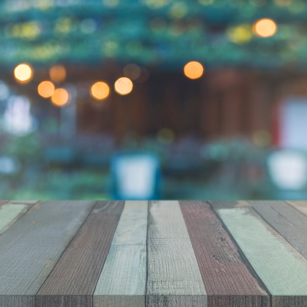 Drewniany stołowy wierzchołek przed ogródem z zamazanymi bokeh światłami