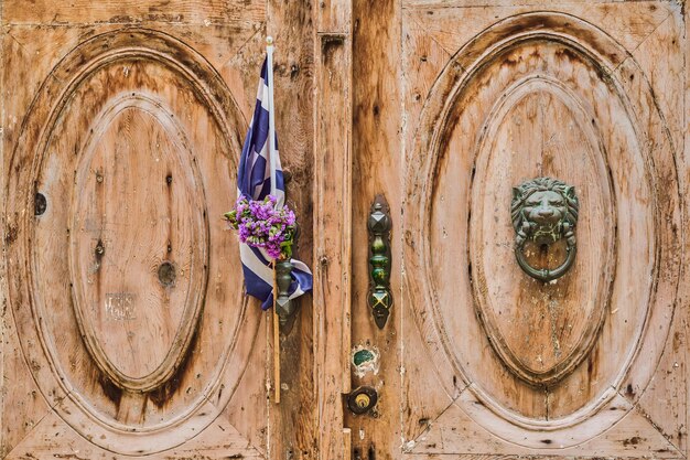 Drzwi starego domu ozdobione flagą Grecji i wieńcem Protomaya miasto Rodos wycieczka do popularnych miejsc archipelagu Dodekanez Grecja
