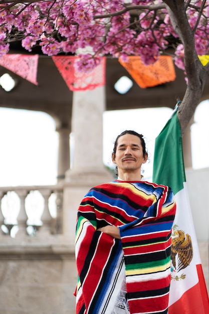 Bezpłatne zdjęcie dumny mężczyzna trzymający meksykańską flagę średni strzał
