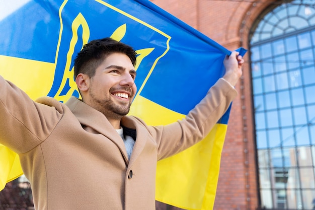 Dumny mężczyzna trzymający ukraińską flagę średni strzał