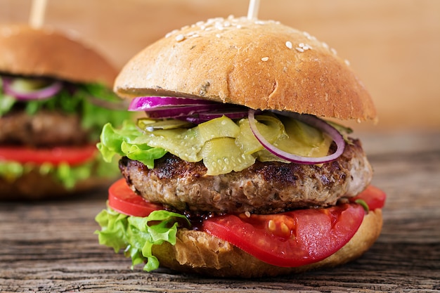 Duża kanapka - burger hamburgerowy z wołowiną, pomidorem, serem i ogórkiem kiszonym.