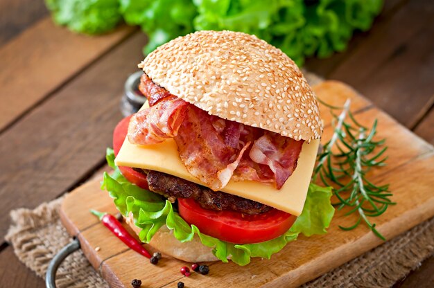 Duża kanapka - burger hamburgerowy z wołowiną, serem, pomidorem i smażonym boczkiem