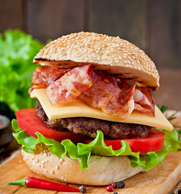 Duża kanapka - burger hamburgerowy z wołowiną, serem, pomidorem i smażonym boczkiem