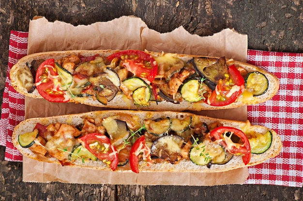 Bezpłatne zdjęcie duża kanapka z pieczonymi warzywami (cukinia, bakłażan, pomidory) z serem i tymiankiem na starym drewnianym tle
