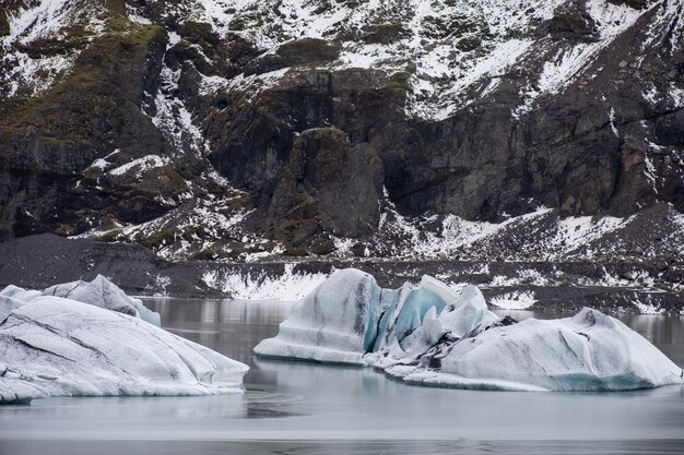 Duże kawałki słodkowodnego lodu w zamarzniętym jeziorze otoczonym skalistymi górami