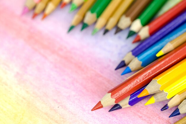 Duże kolorowe ołówki zbliżenie na kolorowym tle z kolorowymi kredkami