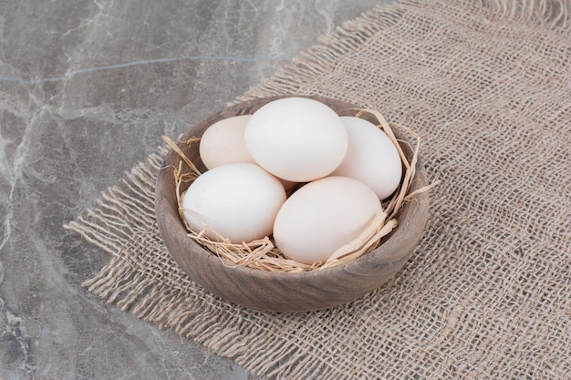Dużo świeżych białych jaj kurzych na drewnianej misce. Zdjęcie wysokiej jakości