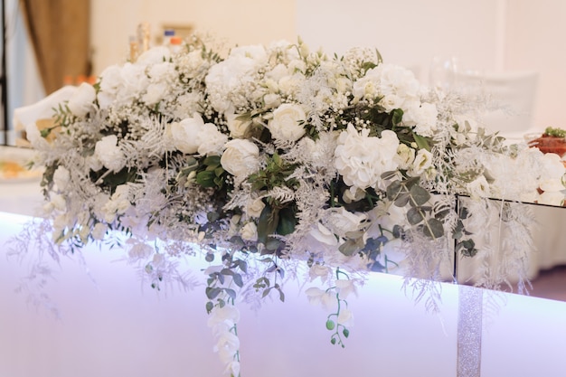 Duży bukiet z białych róż i eukaliptusa stoją na stole