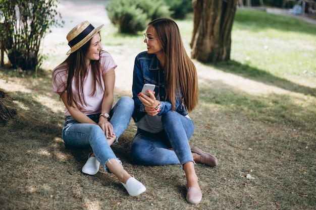 Bezpłatne zdjęcie dwa dziewczyna przyjaciela siedzi w parku