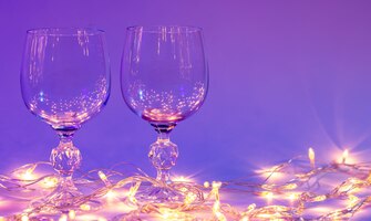 Bezpłatne zdjęcie dwa kieliszki do wina i girlanda w neonowym oświetleniu walentynki w tle