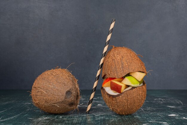 Dwa kokosy ze słomką i plasterkami jabłka