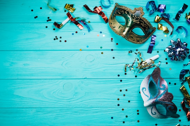Bezpłatne zdjęcie dwa maskarada karnawałowa maska z confetti nad błękitnym stołem
