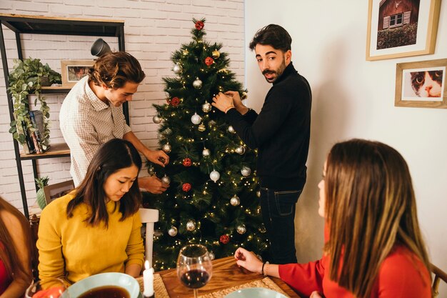 Dwa przyjaciela dekoruje drzewa przy boże narodzenie gościem restauracji