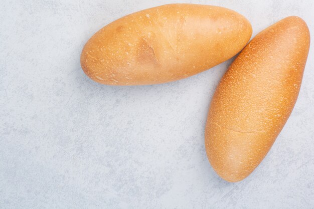 Dwa świeże bochenki chleba na kamiennej powierzchni