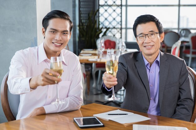 Dwa szczęśliwy przedsiębiorców posiadających kieliszki do szampana