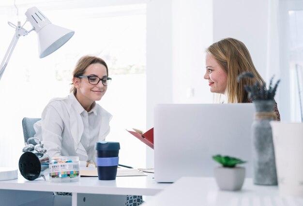 Dwa uśmiechniętego bizneswomanu opowiada w biurze