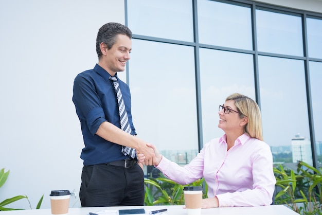 Dwa uśmiechniętych partnerów biznesowych handshaking przy plenerową biurową kawiarnią.