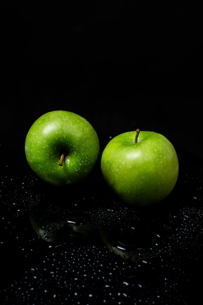 Bezpłatne zdjęcie dwa zielone jabłko na czarnym tle