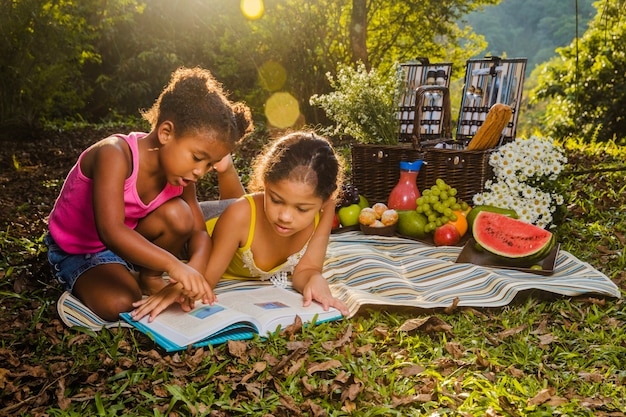 Dwie dziewczynki czyta na ściereczkach piknikowych
