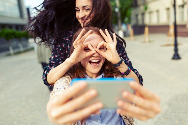 Dwie dziewczyny co śmieszne selfie na ulicy, wspólna zabawa