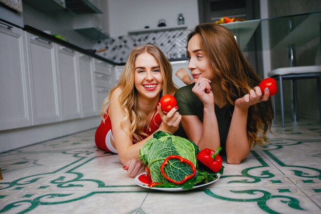 Dwie dziewczyny sportowe w kuchni z warzywami