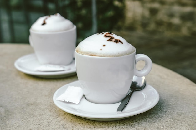 Bezpłatne zdjęcie dwie filiżanki cappuccino w kawiarni na świeżym powietrzu