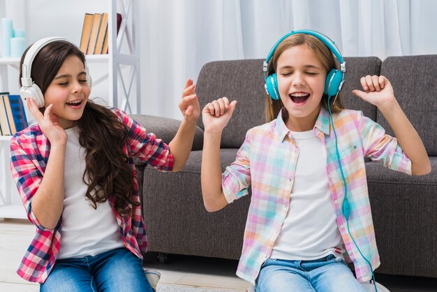 Dwie koleżanki, ciesząc się muzyką na słuchawkach w domu