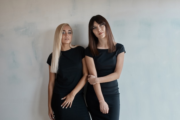 Bezpłatne zdjęcie dwie ładne kobiety w czarnej sukience kryty