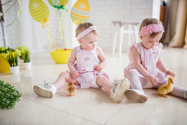 Dwie Małe Dziewczynki W Różowych Sukienkach Bawią Się Na Podłodze W Studiu Z Wielkanocnym Wystrojem